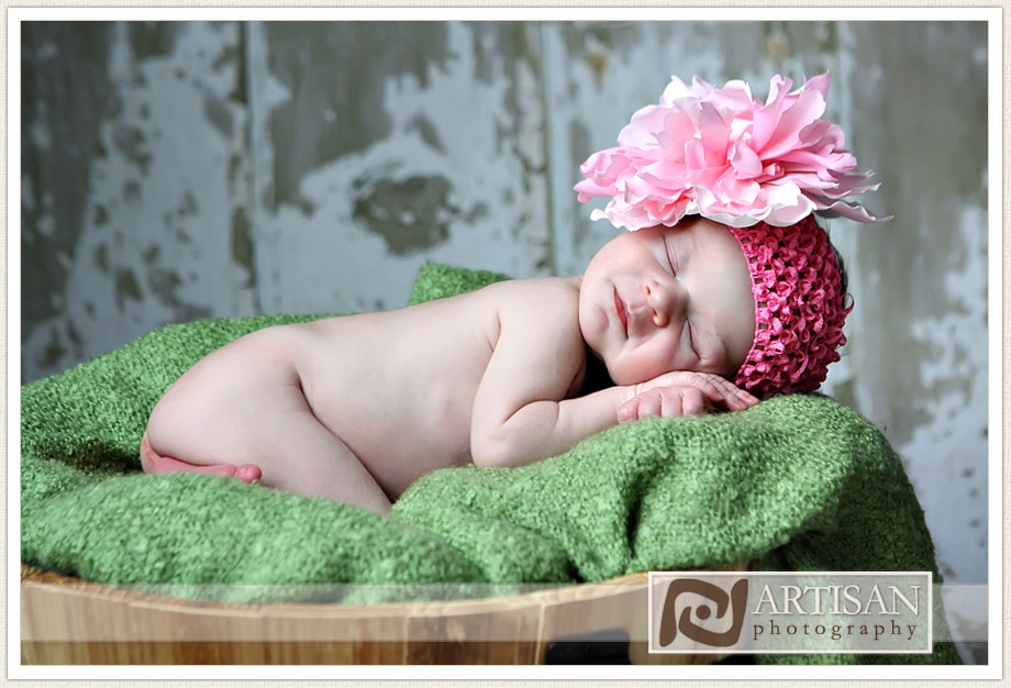 baby girl smiling with pink bow in a basket