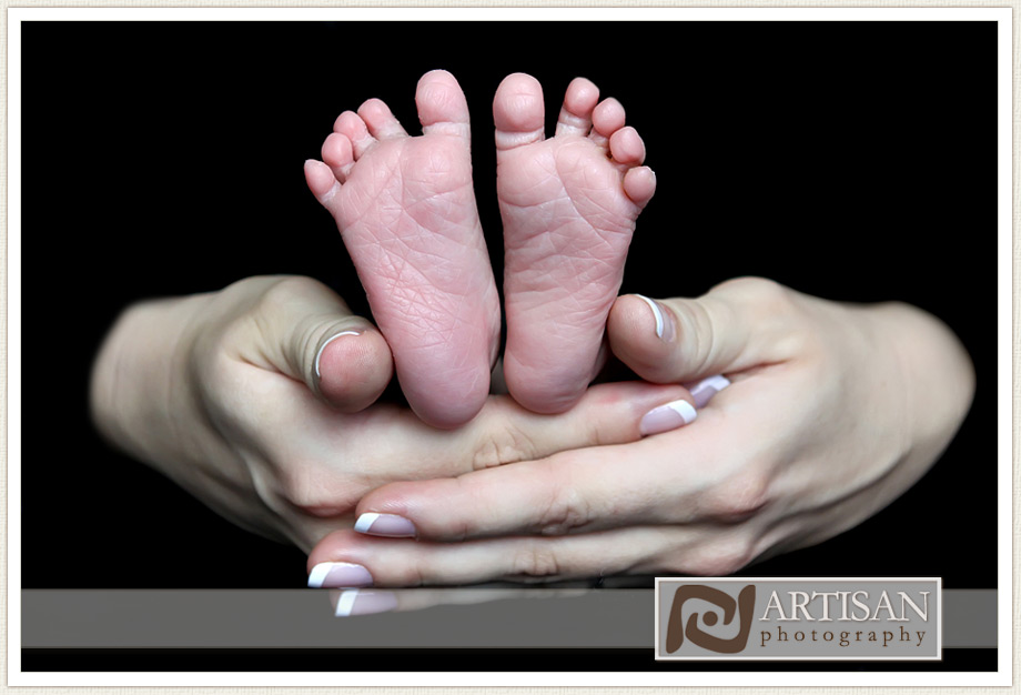 baby feet in hands with black background