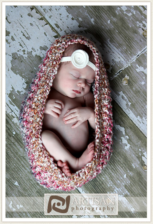 newborn baby girl in cocoon on rustic floor
