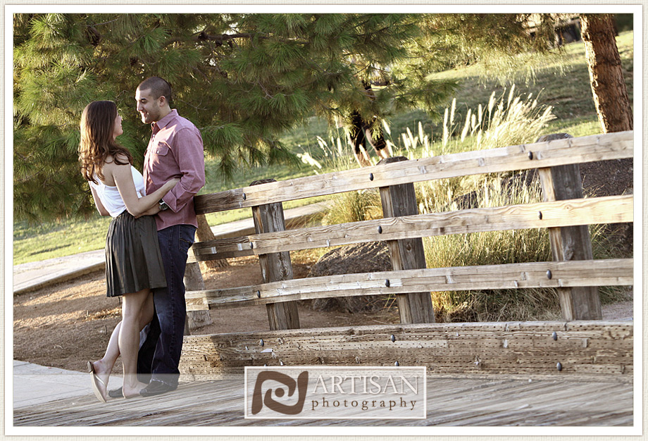 engagement photos at the park in Gilbert couple leaning on bridge fence