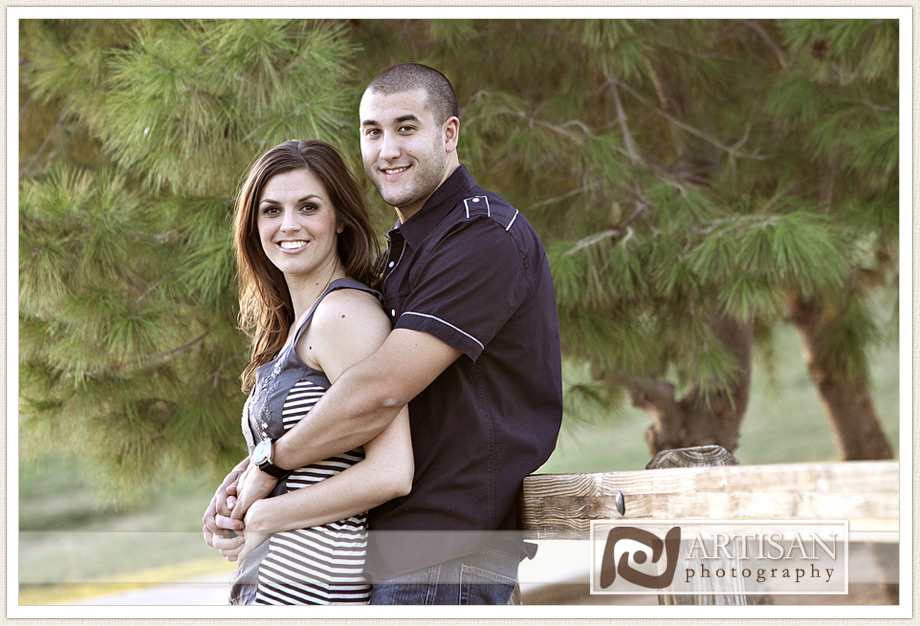 engagement photos at the park in Gilbert couple leaning on bridge fence