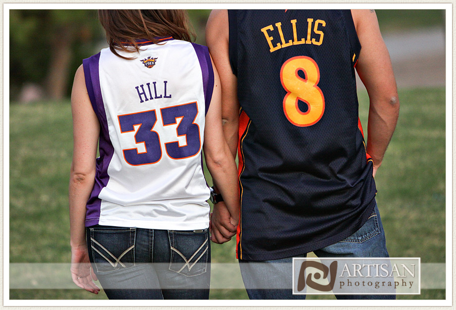 engagement photos at the park in Gilbert couple with sports jerseys kissing from the back