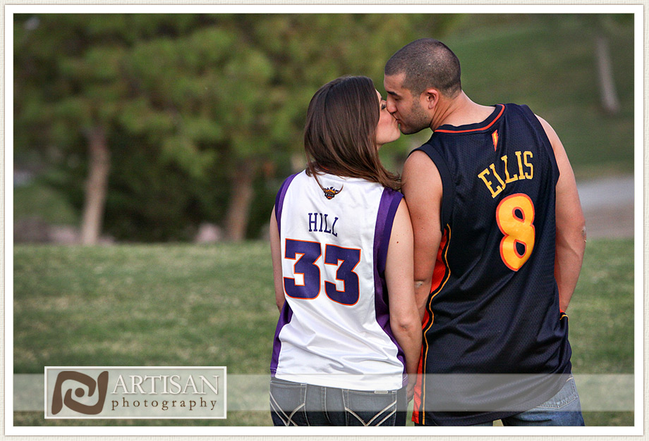 engagement photos at the park in Gilbert couple with sports jerseys kissing from the back