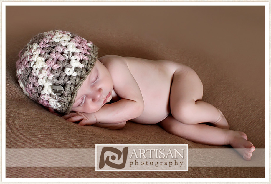 newborn baby girl photo on brown blanket and brown, white and pink hat