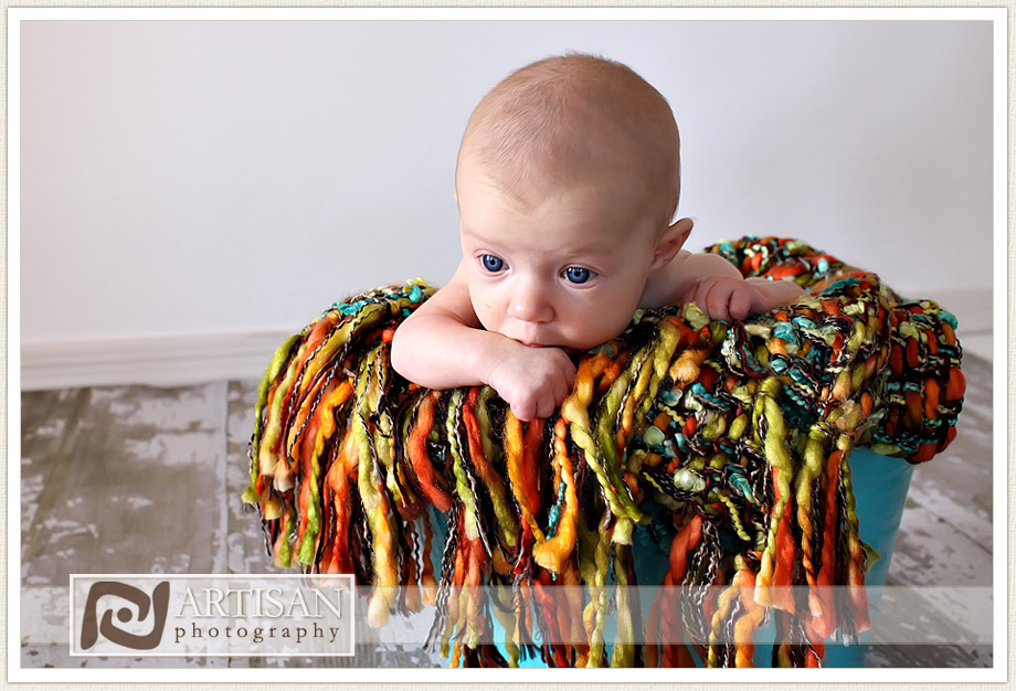 Baby girl in blue basket with a very colorful blanket 