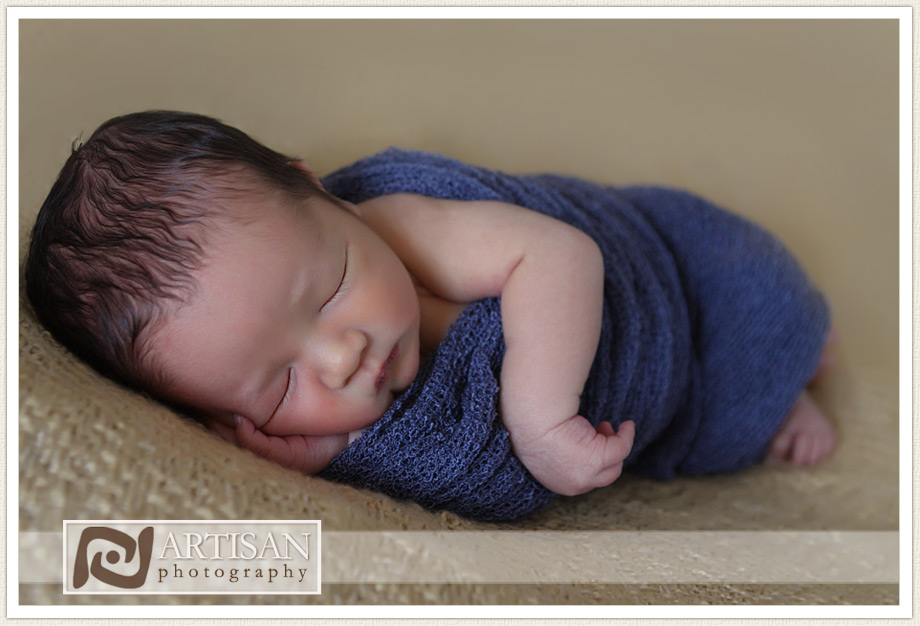 young baby on caramel fabric in blue wrap