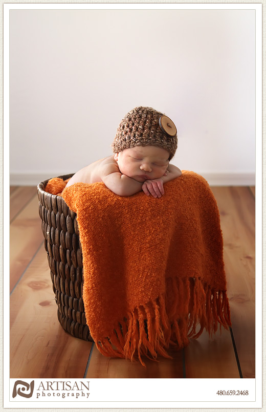 baby in basket with orange blanket