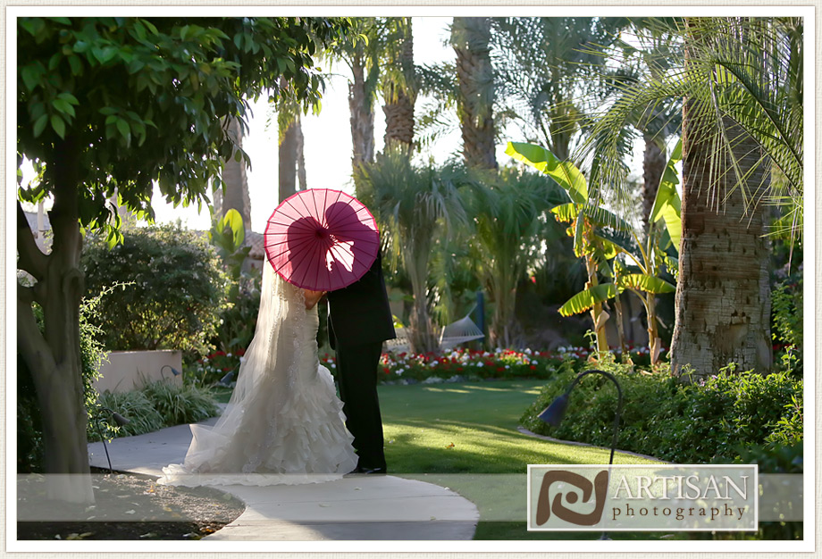 Royal Palms Wedding image of bride and groom kissing behind pink parasol