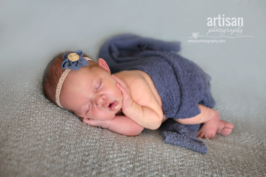 baby girl laying on blanket with flower headband and blue blanket