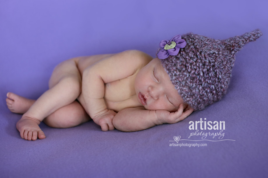 baby girl laying on blanket with flower elf hat lavander background