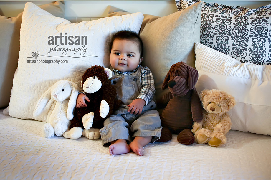 Baby with stuffed animals on top of his bed