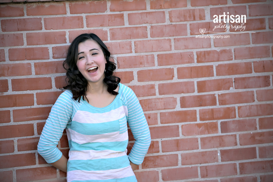 High School Senior photo of Girl leaning against a red brick wall