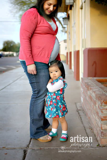 close up shot of toddler hugging mother's leg showing a pregnancy tummy