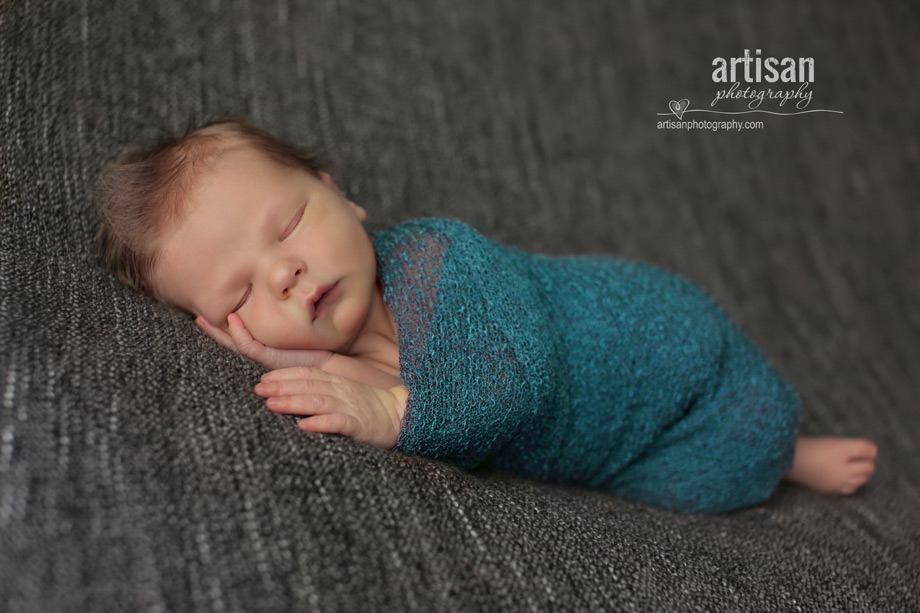 professional photo of newborn baby on grey background and a blue wrap