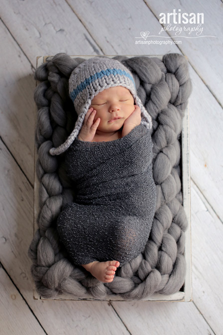 professional photo of newborn baby on grey background and a blue and grey hat