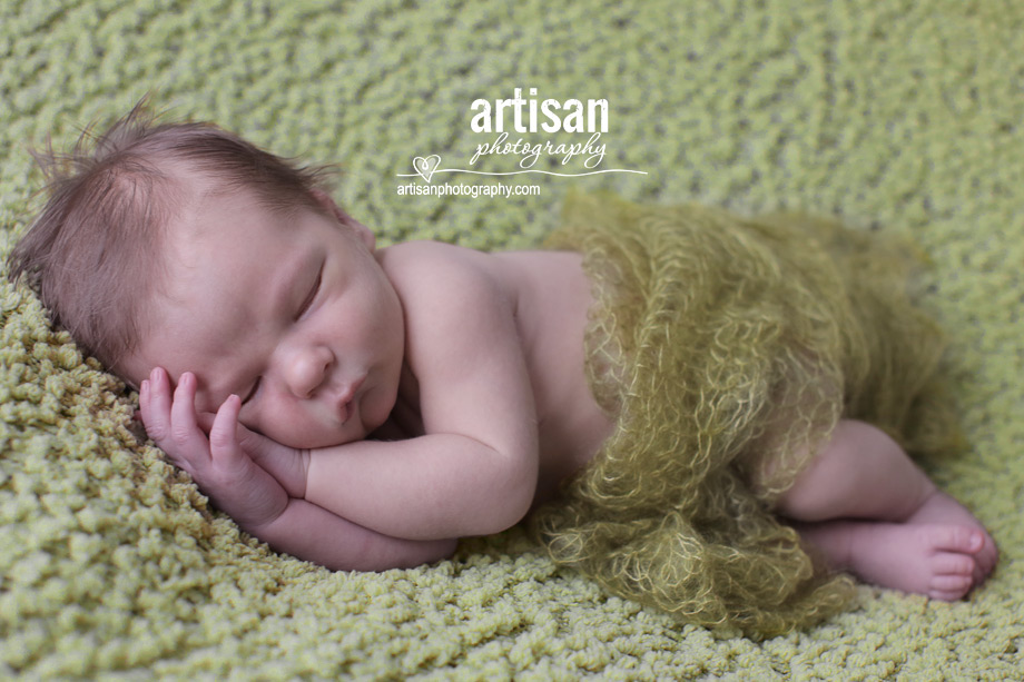 professional photo of newborn baby laying on his side on green blanket