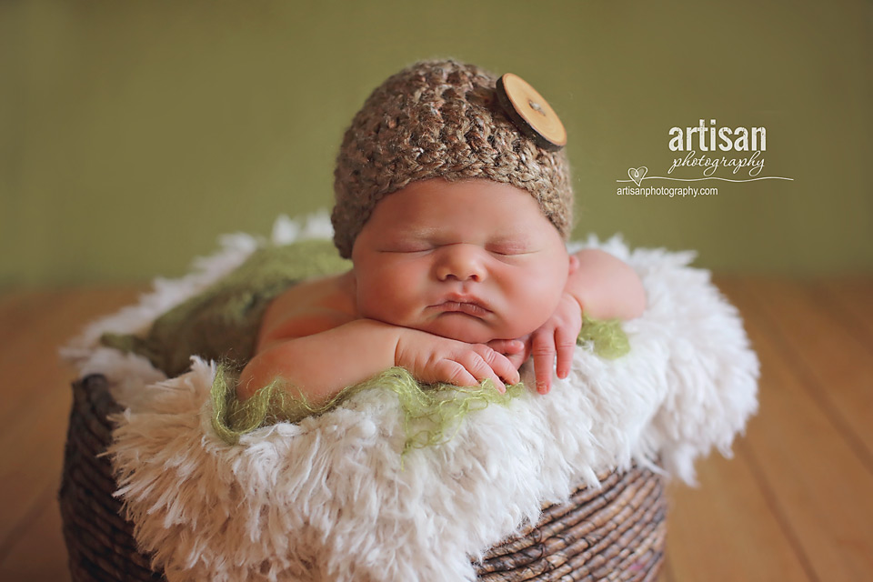 newborn baby boy photo laying on a basket with button hat in Carlsbad California