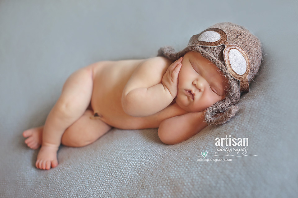 newborn baby boy laying on a blue blanket with an aviator hat in Carlsbad, California