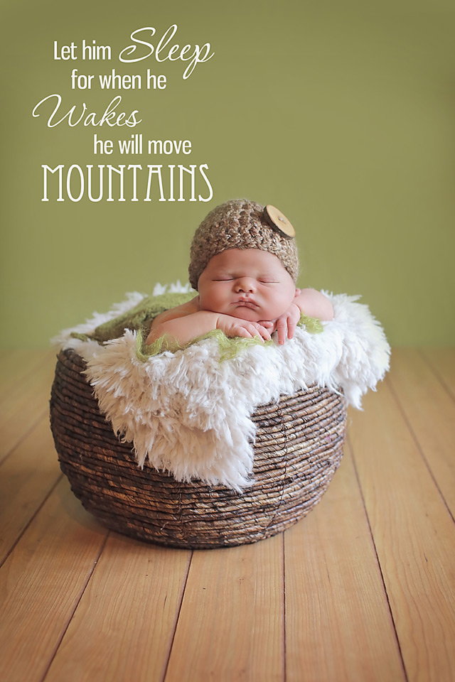 newborn baby boy laying on a brown wicker basket with a brown button hat hat in Carlsbad california