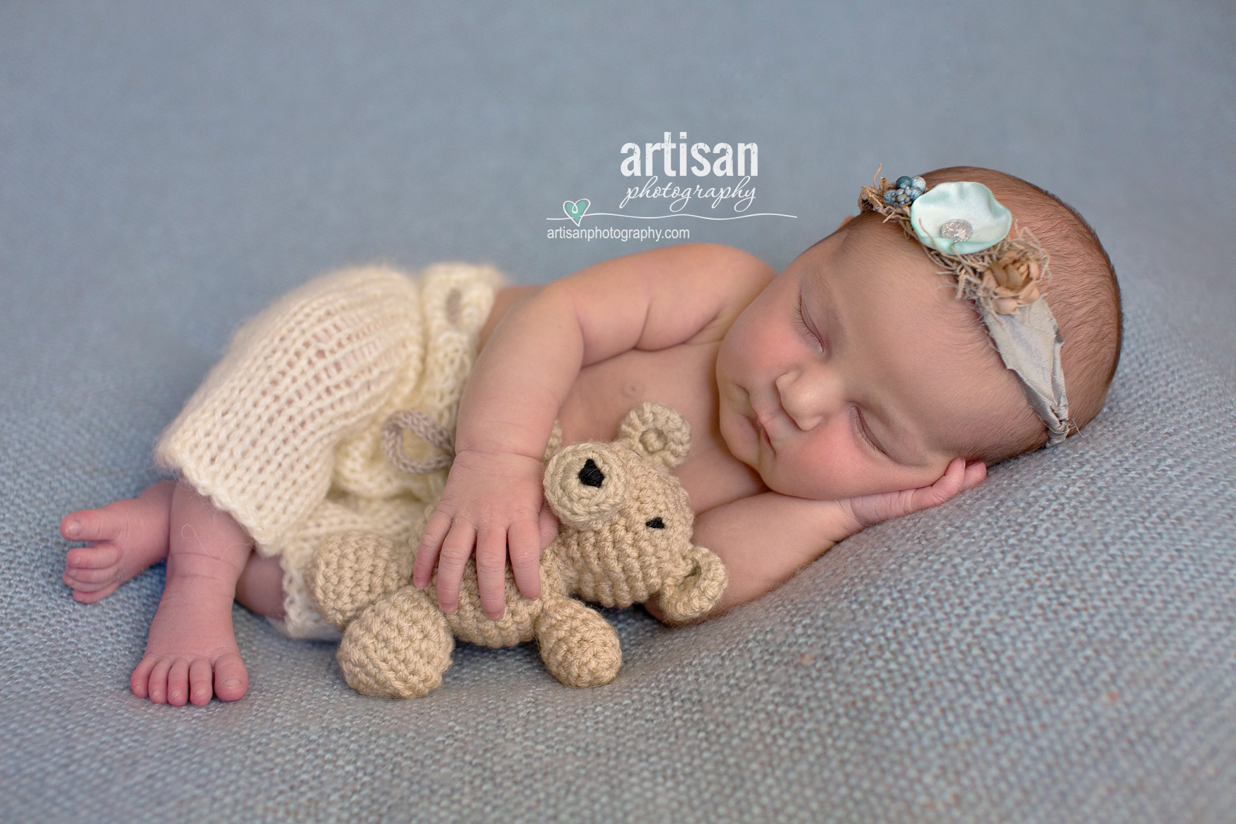 photo Newbon baby girl holding teddy bear photographed by Artisan Photography