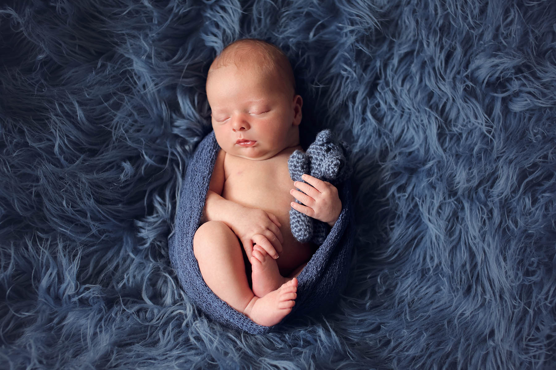 Newborn baby boy on blue flokati rug photographed by carlsbad baby photographer