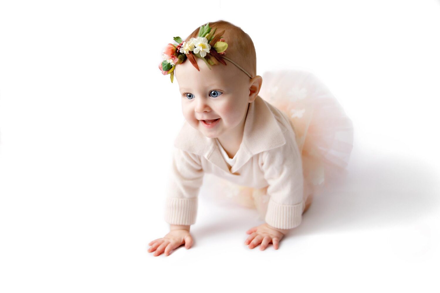 baby girl in pink tutu crawling and smiling studio