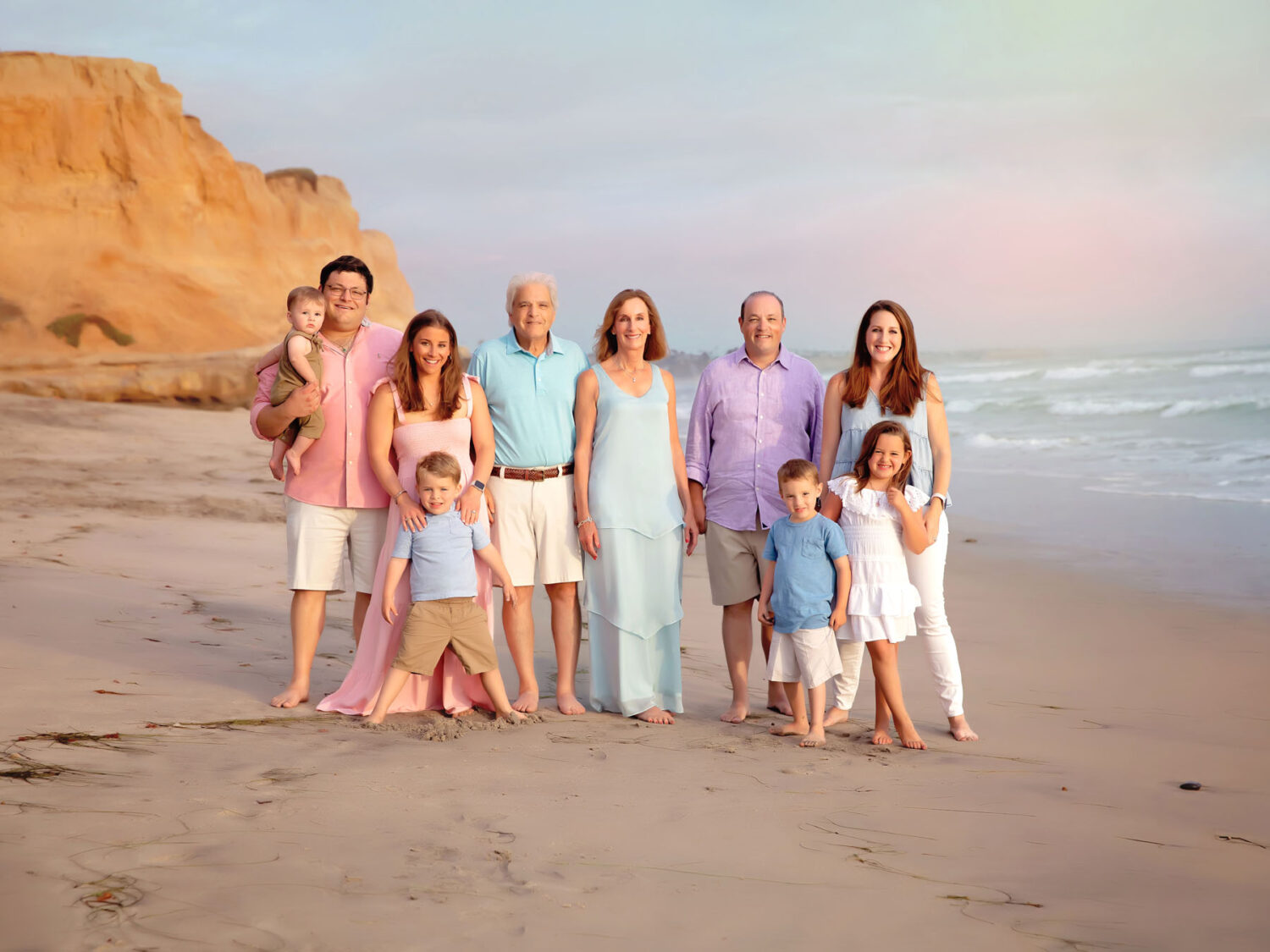 Extended Family photo on the Beach with 6 adults and 4 kids. Sand, ocean and cliffs in the background