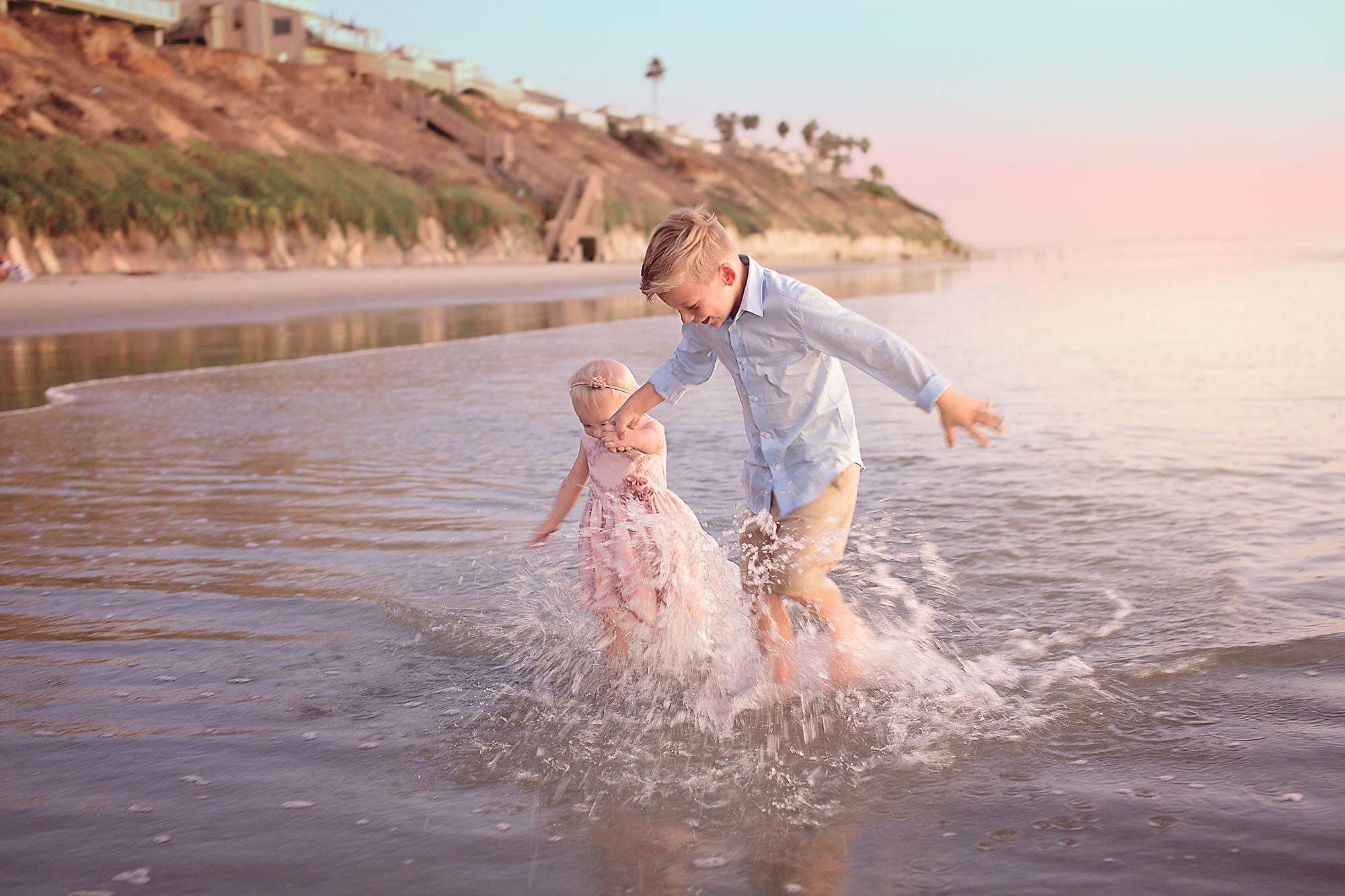 Siblings older boy and toddler girl playing on the beach 